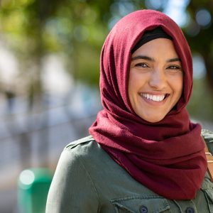 the photo shows a woman with dark eyes standing outside and smiling straight at the camera