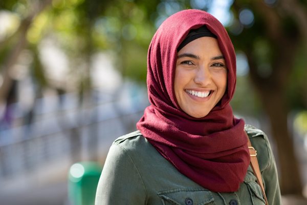 the photo shows a woman with dark eyes standing outside and smiling straight at the camera