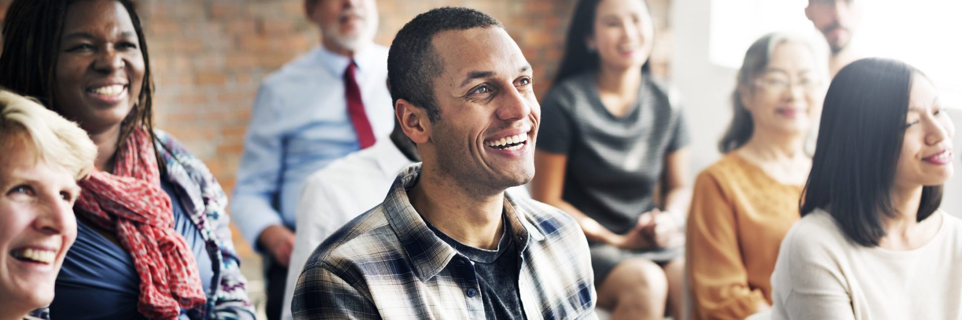 a group of people are sitting inside on chairs and are all looking towards the front of the room smiling