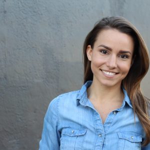 a young woman with dark eyes and long straight dark hair is smiling straight at the camera