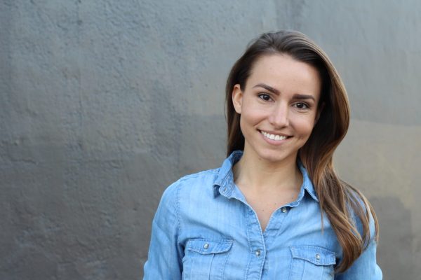 a young woman with dark eyes and long straight dark hair is smiling straight at the camera